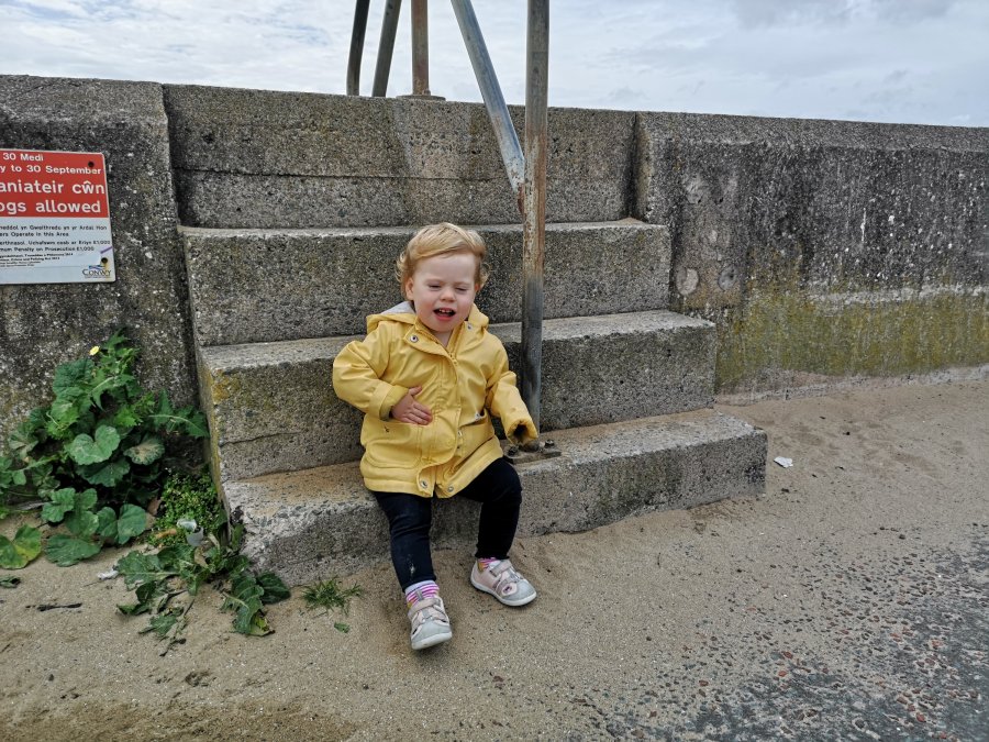 Toddler in raincoat on beach steps